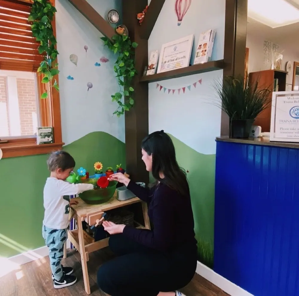 A caregiver and child playing together with flowers at Traina's center