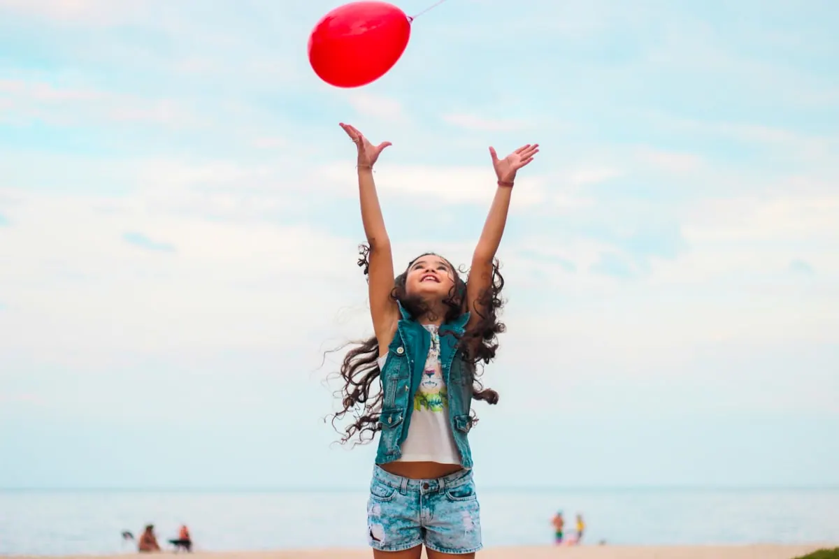 A child reaches up joyfully for a balloon.