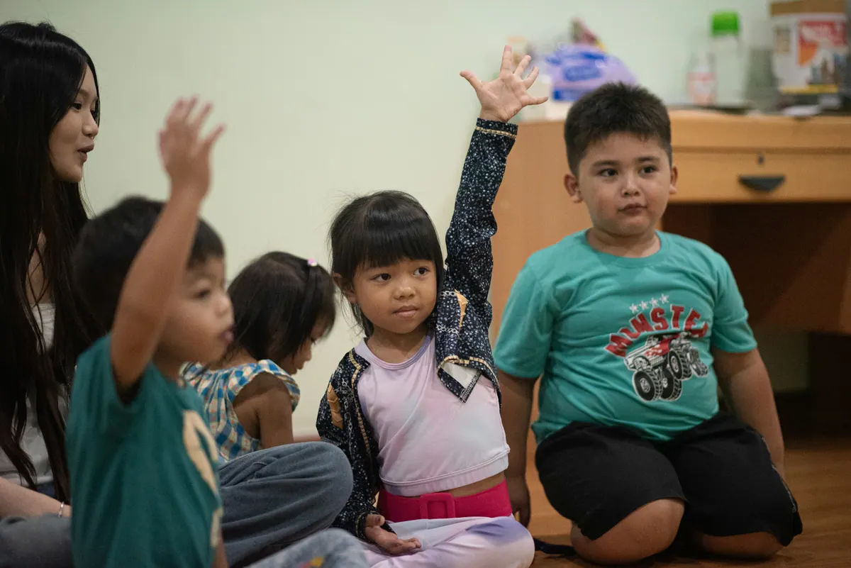 A Traina clinician working with a small group of children, one child raising her hand