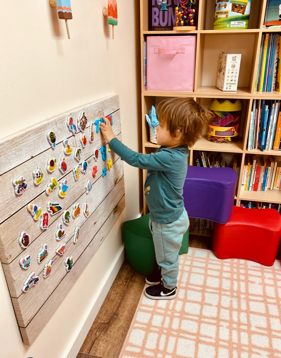 A young child matching picture cards on a wall during a session