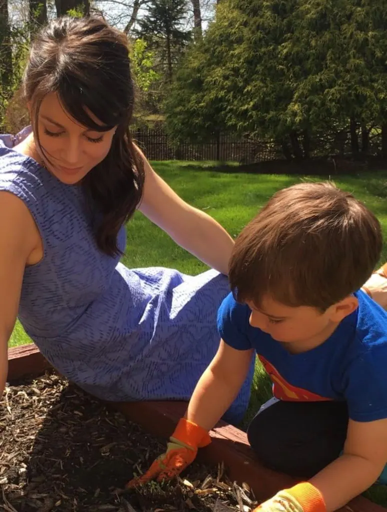 A parent and child planting together in a backyard garden