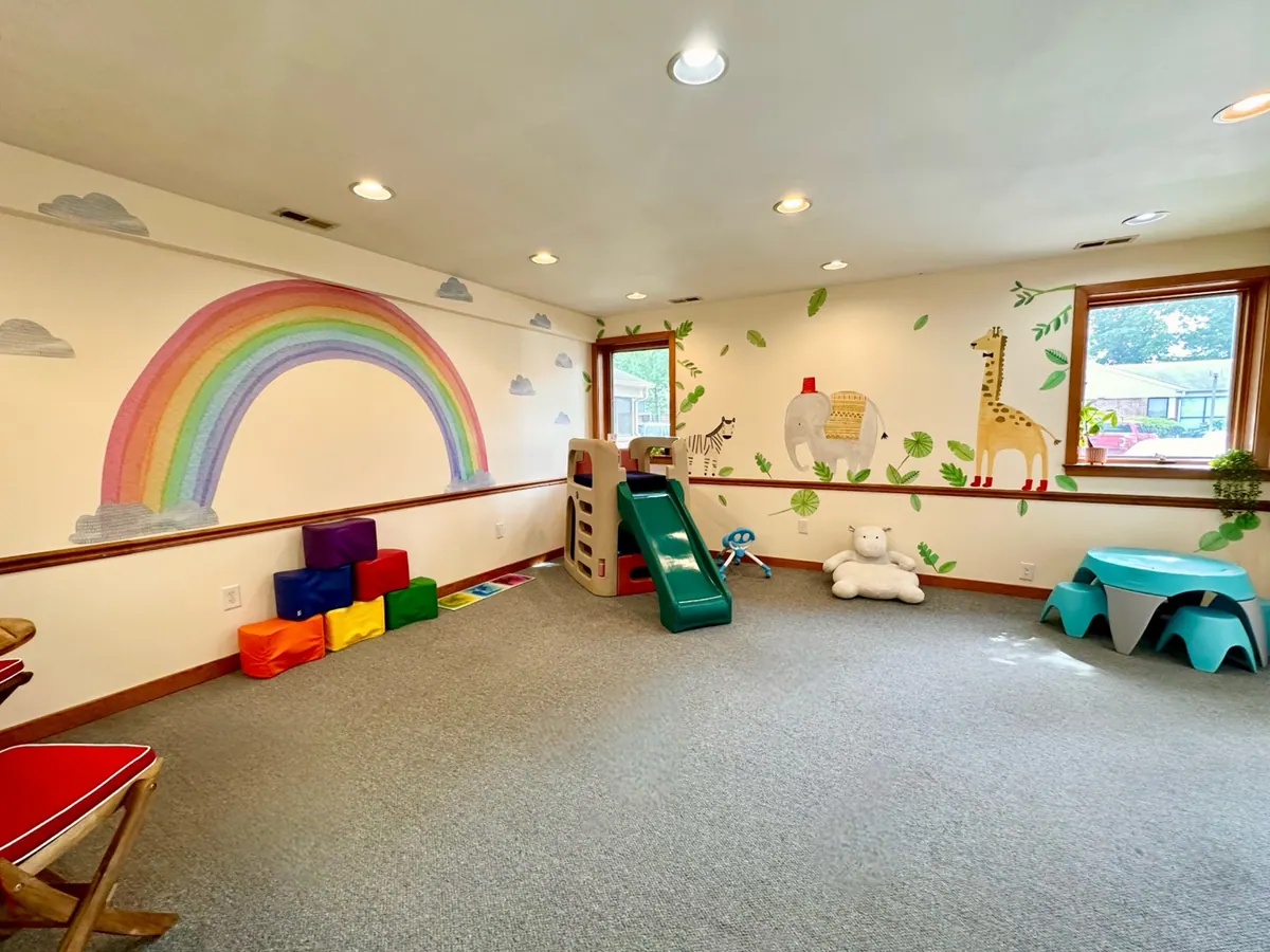 A bright therapy room at the Traina Behavioral center with a rainbow mural, soft foam blocks, and a small slide