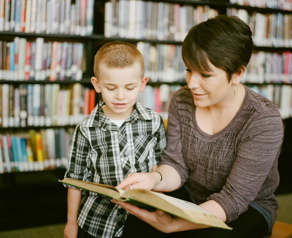 A teacher reading with a student in a school library