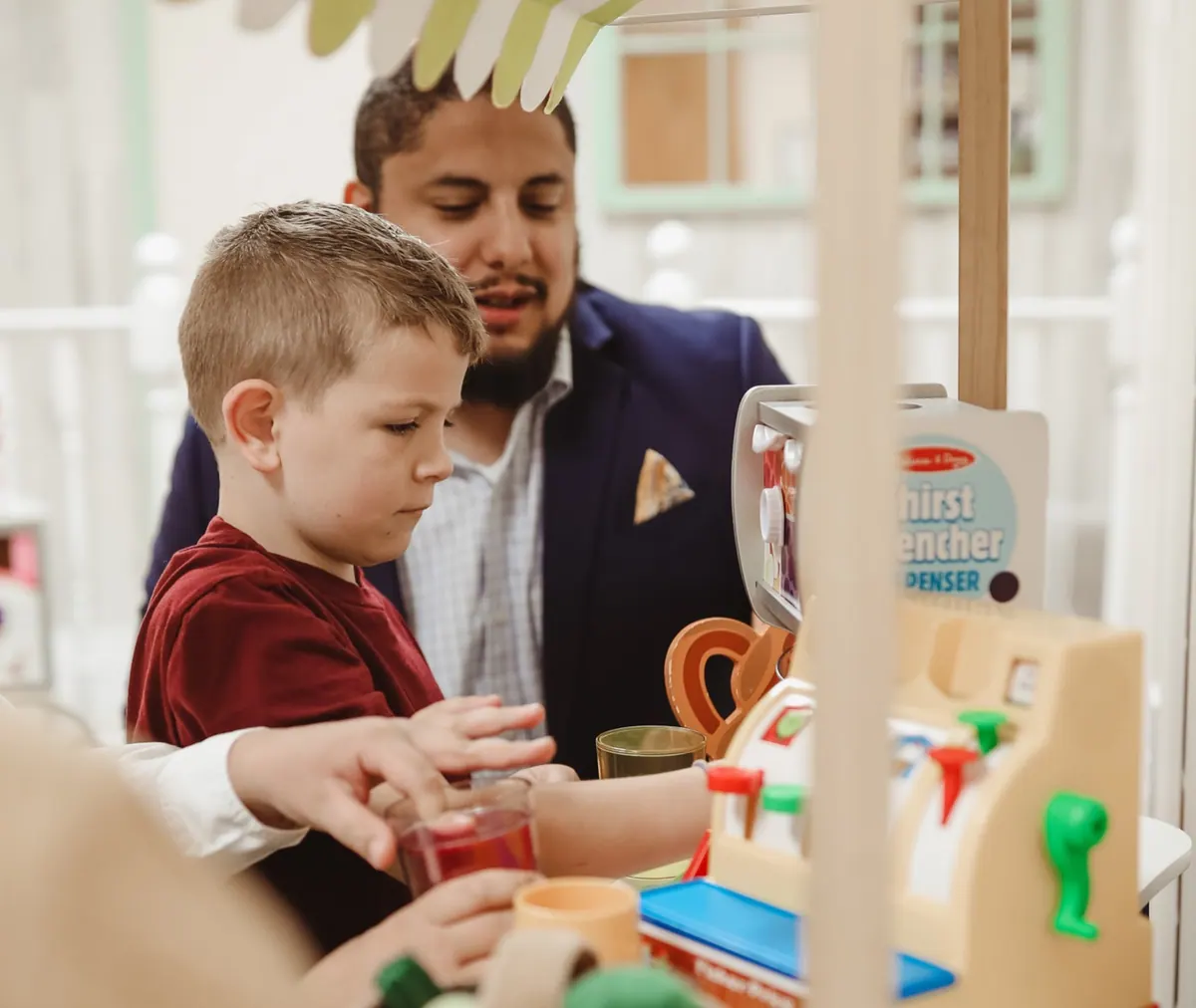 A Traina team member and a young boy playing together at a pretend grocery store